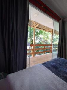 a bedroom with a bed and a large glass window at Castelo de Madeira in Blumenau