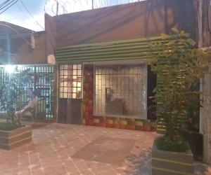 um edifício com um portão e um homem sentado num banco em Casa Turistica Zamboss em Montería