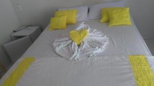 a white bed with a heart towel on it at POUSADA FJ MELO in Porto De Galinhas