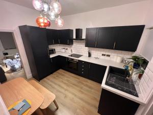 a small kitchen with black cabinets and a table at Altrincham Terrace - 2 Bedroom House - Free Parking - Sleeps 6 - Near Tram Stop in Manchester