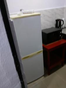 a white refrigerator in a kitchen next to a microwave at chinaka guest house 24hr light in Lagos