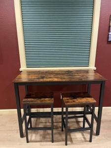 una mesa de madera con un par de taburetes bajo una ventana en Cedar Mountain Suite D, en Grants Pass