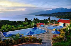 uma piscina com guarda-sóis e vista para a água em ASTON Niu Manokwari Hotel & Conference Center em Manokwari