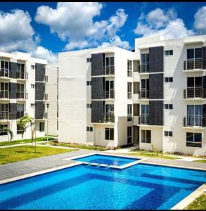 um edifício de apartamentos com uma piscina em frente em Departamento vacacional em Playa del Carmen