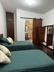 2 camas en una habitación con sábanas verdes y una ventana en Casa Praxedis, en Santiago