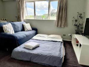 a living room with a blue couch and a bed at Albany Modern Private 2 bedroom 2 bathroom with Full Kitchen Netflix in Auckland