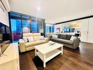 ein Wohnzimmer mit einem Sofa und einem Tisch in der Unterkunft Readyset Apartments at Manhattan in Melbourne