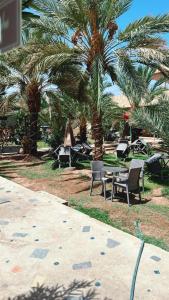 a table and chairs and palm trees in a park at Appart-hotel la lune du desert in Erfoud