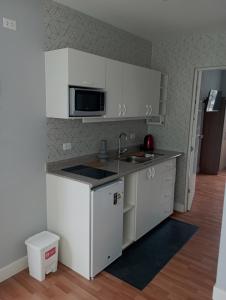 a kitchen with white cabinets and a sink and a microwave at Like/Home in Lima