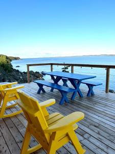 einen Picknicktisch und Stühle auf einer Terrasse mit Meerblick in der Unterkunft The View suites and breakfast in Triton, Newfoundland in Pilleyʼs Island