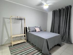 um quarto com uma cama e uma ventoinha de tecto em AeK apartamento conforto praia em Peruíbe