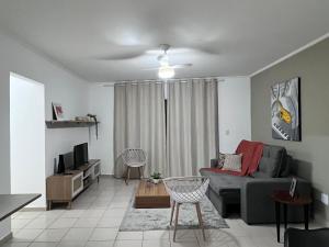 a living room with a couch and a tv at AeK apartamento conforto praia in Peruíbe