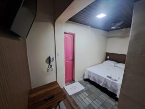 um pequeno quarto com uma cama e uma porta vermelha em Pousada Nova Ludovicense em São Luís
