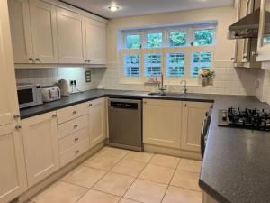 een keuken met witte kasten, een wastafel en een fornuis bij New - Beautiful Countryside Home in Streatley