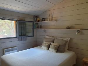 ein kleines Schlafzimmer mit einem weißen Bett mit Kissen in der Unterkunft Gîtes "Les Cabanes de Carelle" entre Camargue et Cévennes in Aspères + 75 Fotos