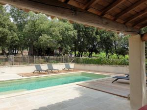 a swimming pool with two lounge chairs and a wooden pergola at Les Cabanes de Carelle in Aspères