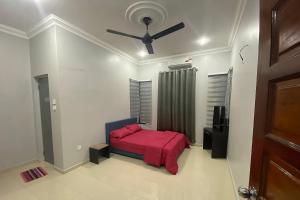 - une chambre avec un lit rouge et un ventilateur de plafond dans l'établissement Syikin Homestay - Private Pool, à Bedung