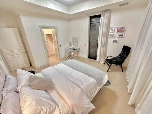 a white bedroom with a bed and a chair at MacArthur Chambers in Brisbane