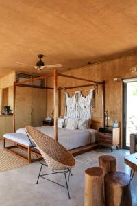 een slaapkamer met een bed en een stoel bij Mexico en la Piel in Valle de Guadalupe