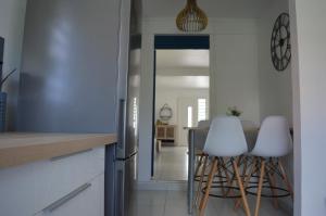 a kitchen with white stools and a table in it at Maison La Caféière in Saint-Claude +6 photos