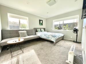 ein Wohnzimmer mit einem Sofa und einem Bett in der Unterkunft Modern Private 2 Bedroom Home-unit in Albany with Netflix in Auckland
