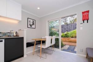 eine Küche und ein Esszimmer mit einem Tisch und einem Fenster in der Unterkunft Modern Private 2 Bedroom Home-unit in Albany with Netflix in Auckland