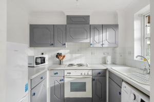 - une cuisine blanche avec des placards gris et des appareils blancs dans l'établissement Cozy Luton Town Centre Retreat, à Luton