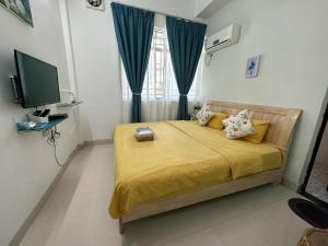 een slaapkamer met een bed met gele lakens en een televisie bij House of Wisdom in Renhua