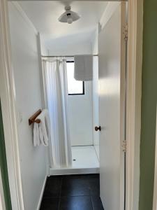 biała łazienka z prysznicem i oknem w obiekcie Alpine Motel w mieście Ohakune