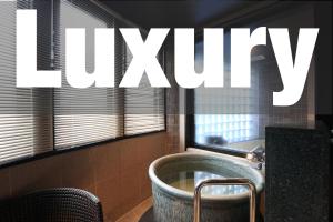 a bathroom with a tub and a window with the word luxury at 時のホテル in Toki
