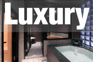 a bathroom with a tub and a sign that reads luxury at 時のホテル in Toki