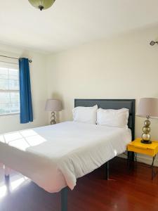 a large white bed in a bedroom with a blue curtain at Charming Century City Condo in Los Angeles