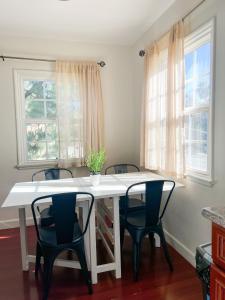a white table with four chairs and two windows at Charming Century City Condo in Los Angeles