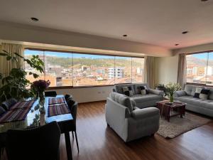ein Wohnzimmer mit Sofas, einem Tisch und einem großen Fenster in der Unterkunft hermoso departamento en zona residencial de cusco in Cusco