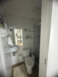 a white bathroom with a toilet and a sink at Village ITACIMIRIM in Camaçari
