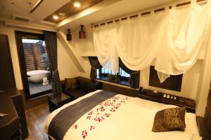 a bedroom with a bed with red flowers on it at HOTEL PetitBali Higashi-Shinjuku in Tokyo