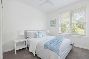 a white bedroom with a bed and a window at Botanical Oasis in Frankston
