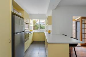 a kitchen with yellow cabinets and a white refrigerator at Botanical Oasis in Frankston