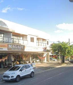 a white car parked in front of a building at AeK apartamento conforto praia in Peruíbe