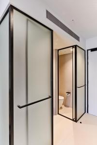 a bathroom with sliding glass doors and a toilet at Central Club Hotel - North Melbourne in Melbourne