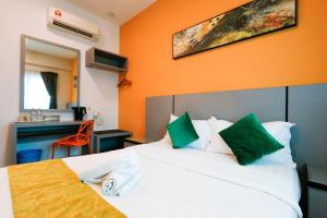 a hotel room with a white bed with green pillows at Travelland Hotel in Ipoh