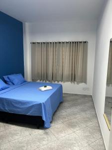 a bedroom with a bed with blue sheets and a window at HOSTEL CAMINHO DA FE in Aparecida