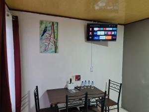 ein Esszimmer mit einem Tisch und einem TV an der Wand in der Unterkunft Cabins Guayabon #2, AC, Arenal Volcano La Fortuna in Fortuna