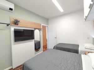 a hotel room with two beds and a tv at Apartamento Sant'Ana in Porto Alegre