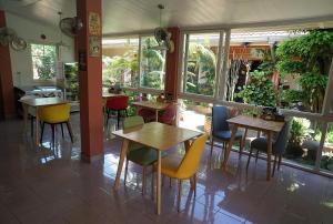 een restaurant met tafels, stoelen en ramen bij Udon Thai House Resort & Hotel in Udon Thani