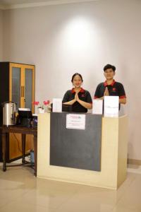 un hombre y una mujer parados detrás de un mostrador en Pondok Indah24 Hotel en Yakarta