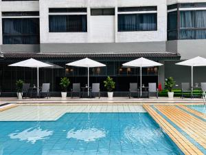 una piscina con sombrillas, mesas y sillas en The Bed Bukit Bintang, en Kuala Lumpur