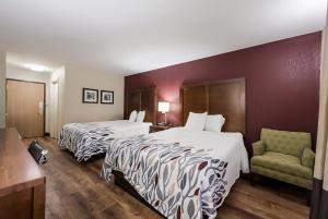 una habitación de hotel con 2 camas y una silla en Red Roof Inn Newport News - Yorktown, en Yorktown