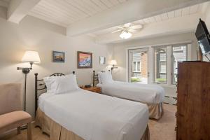a bedroom with two beds and a tv and a chair at Cottonwoods 1-D in Aspen