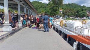 un gruppo di persone in piedi su un molo accanto a una barca di Gilibooking ticket a Padangbai